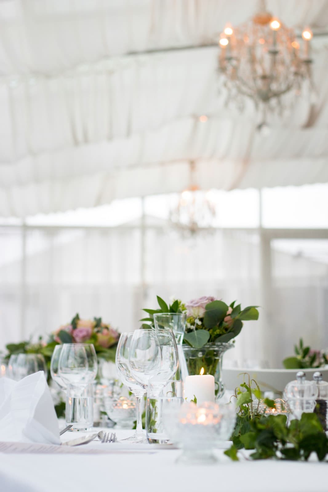 Ein weiß gedeckter Tisch mit Blumen, Kerzen und Gläsern