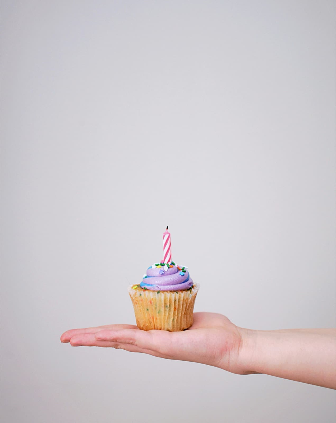 Ein Cupcake mit einer Kerze auf einer Hand